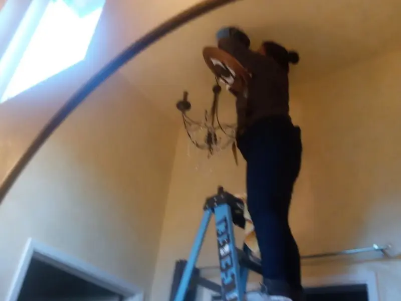 Electrician installing a chandelier in a Tiptonville residence